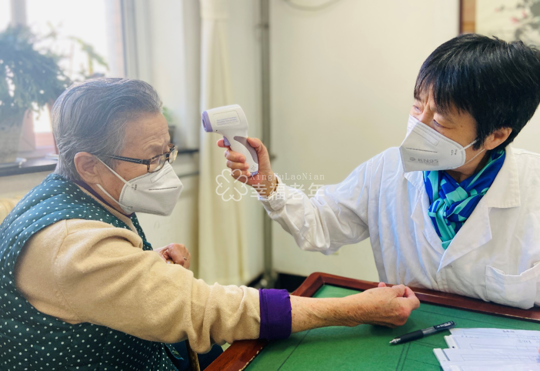 ▲北京市东城区三和老年公寓内,医护人员正为老人测量体温。新京报资料图